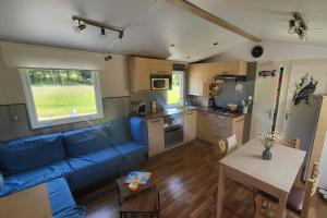 a living room with a blue couch and a kitchen at L'échappée Verte in Chambellay