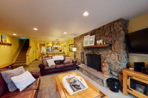 a living room with a stone wall with a fireplace at Beaver Creek West 26 in Avon