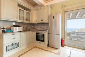 una cucina con mobili bianchi e un frigorifero di Manolia Luxury Private house by Mykonian Kazarte a Kalo Livadi