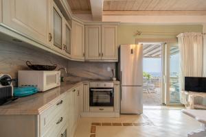 una cucina con armadi bianchi e frigorifero in acciaio inossidabile di Manolia Luxury Private house by Mykonian Kazarte a Kalo Livadi