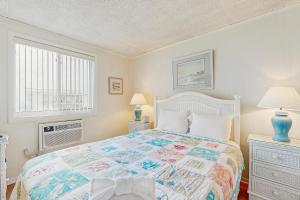 een slaapkamer met een bed, 2 lampen en een raam bij Colonial Unit #502 in Ocean City