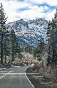 Una carretera vacía frente a una montaña cubierta de nieve en RR-Hideaway_Down_Cyn 104, en June Lake