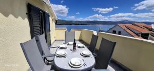 a table on a balcony with a view of the water at Apartmani Brnada in Trogir