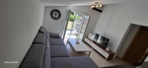 a living room with a couch and a clock on the wall at Apartmani Brnada in Trogir