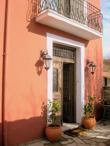 a house with a balcony and a door with potted plants at Archontiko Pantou in Portaria