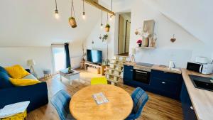 a living room with a wooden table and a kitchen at Logement cosy et confortable. in Thourotte
