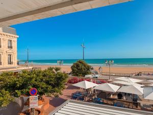 Una playa con mesas y sombrillas y el océano. en Studio au pied de la plage, vue mer Les Sables - 4 personnes, en Les Sables-dʼOlonne