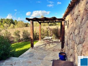 a patio with a table and chairs and a stone wall at CASA FELICE - 1 Chambre - Climatisation - Jacuzzi Prrivee in San-Gavino-di-Carbini