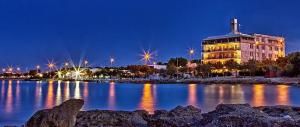 a large building with lights on the water at night at Aurora e Alba in Casalabate