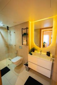 a bathroom with a sink and a toilet and a mirror at Amberdi Noria Apartment Marrakech in Marrakech