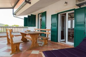 a wooden table and bench on a porch with green shutters at Andrijas Apartments in Tribunj