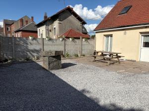 a picnic table and a bench in a backyard at Charmante maison de campagne in Gouzeaucourt
