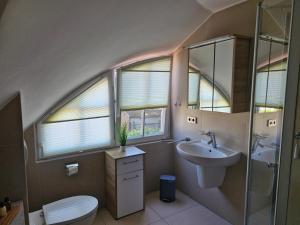 ein Bad mit einem Waschbecken, einem WC und Fenstern in der Unterkunft STRANDROSE - 300m zum Strand in Zingst