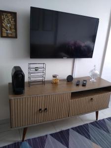 a large flat screen tv on top of a wooden cabinet at Apartamento Morada do Vale 1 andar - Área de Lazer - Estacionamento - Internet e Netflix GRATUITO in Garanhuns