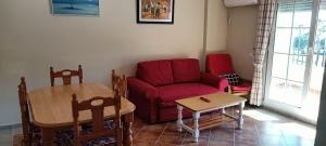 salon z czerwoną kanapą i stołem w obiekcie WIFI Los Cisnes 2 dormitorios Primera Linea playa Ayamonte Isla Canela w mieście Isla Canela