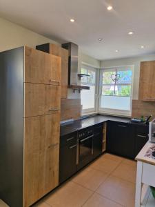 a kitchen with black cabinets and a black refrigerator at STRANDROSE - 300m zum Strand - Kamin - Sauna in Zingst