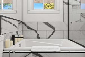 a white bath tub in a bathroom with a window at Nineteen55 4BR Parkside Home in Central Red Deer in Red Deer