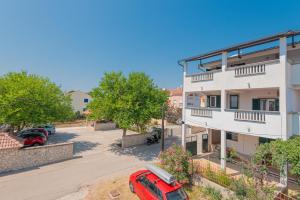 an apartment building with a red car parked next to it at Andrijas Apartments in Tribunj