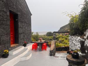 a patio with red doors and red chairs and a table at Casa Do Salgueiro in Calheta +25 photos