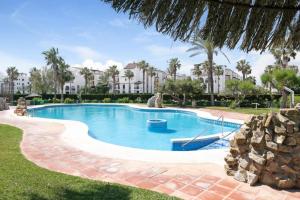 a swimming pool in a resort with palm trees at Apartamentos Atlanterra COSTA Y SOL in Zahara de los Atunes