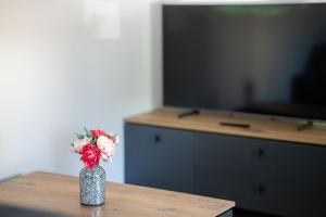 a vase with flowers sitting on a table in front of a tv at Kudirkos namai in Šilutė