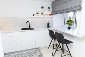 a white kitchen with two chairs and a sink at Kudirkos namai in Šilutė