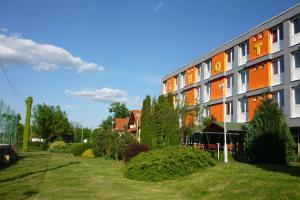 an orange and white building with a yard at Touring & Sport Hotel Siófok in Siófok