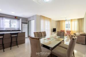 a kitchen and a living room with a glass table at Apto 450m da praia c/ churrasq. e 3 suítes TAH0602 in Meia Praia