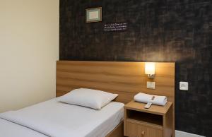 a small bedroom with two beds and a night stand at N Hotel Syariah in Tanjung Pinang 