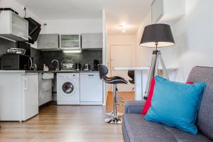 ein Wohnzimmer mit einem Sofa und einer Lampe sowie eine Küche in der Unterkunft Séjour Toulouse Purpan Le D'este in Toulouse
