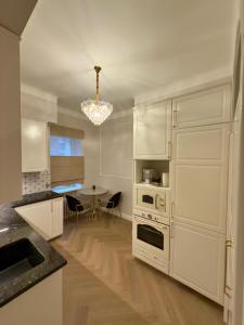 a kitchen with white cabinets and a table and a chandelier at KR Apartment Kaunas in Kaunas