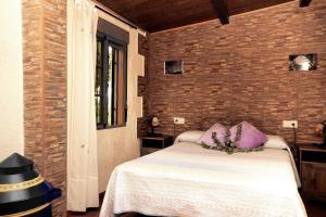 1 dormitorio con 1 cama con almohadas moradas y pared de ladrillo en Mirador Los Cotos, en Torremenga 28 fotos más