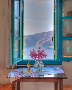 a table with a window with a vase of flowers on it at Pano Gitonia in Aegiali