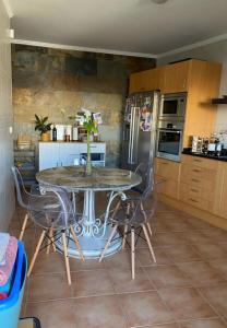 eine Küche mit einem Tisch mit Stühlen und einem Kühlschrank in der Unterkunft MAISON FAMILIALE ENTRE MER ET MONTAGNE Lisbonne in São Bartolomeu