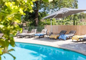 eine Gruppe von Stühlen und einem Sonnenschirm neben einem Pool in der Unterkunft Villa provençale calme avec piscine chauffée 6 ch in Le Rouret