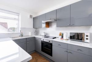 eine Küche mit weißen Schränken und einem schwarzen Gerät in der Unterkunft Chic 3 BR Home with Balcony & Free Parking in Leeds