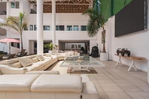 ein Wohnzimmer mit weißen Möbeln und Palmen in der Unterkunft Casa Ferlioni in Temixco