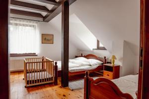 a attic bedroom with two beds and a crib at Pod Kogutem in Cierzpięty