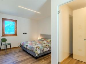 a bedroom with a bed and a chair and a window at Apartment Pettazzuro by Interhome in Verceia
