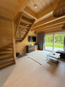 Domy nad Strugą - jacuzzi, las, wieś, rowery, kajaki : غرفة معيشة مع درج خشبي وأريكة