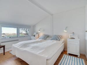 a white bedroom with a large white bed and a window at Holiday Home Githe - from the sea by Interhome in Hals