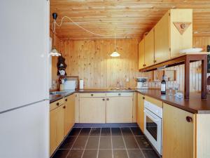 a kitchen with wooden cabinets and a white refrigerator at Holiday Home Githe - from the sea by Interhome in Hals +10 photos