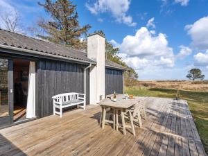 a wooden deck with a table and a bench on it at Holiday Home Githe - from the sea by Interhome in Hals
