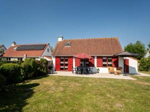 a red and white house with a table and chairs at Holiday Home Polderhuis 9 parking and shared pool by Interhome in De Haan