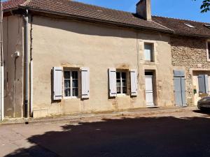 un vecchio edificio con finestre bianche con persiane su una strada di Petite Maison Cosy ad Auxonne