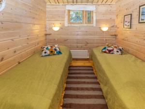 two beds in a room with wooden walls at Holiday Home Savottakämppä by Interhome in Luosto