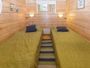 two beds in a room with wooden walls at Holiday Home Savottakämppä by Interhome in Luosto