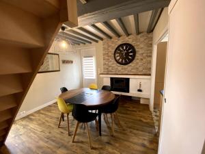 a dining room with a table and chairs and a clock at Gîte de la Consoude - Clécy in Clécy