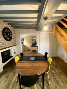 a dining room with a table and chairs and a clock at Gîte de la Consoude - Clécy in Clécy +15 photos