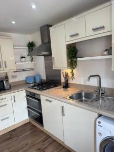 a kitchen with white cabinets and a sink at Town centre abode with gated parking in Shrewsbury +12 photos
